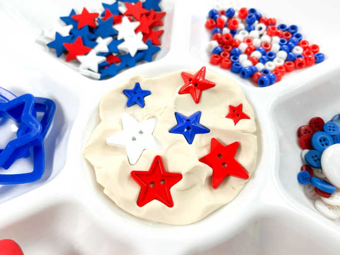 starting the invitation to play putting stars in the white play dough