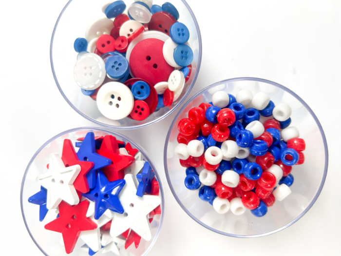bowls of red white and blue materials for sensory bottle, including stars, beads and buttons
