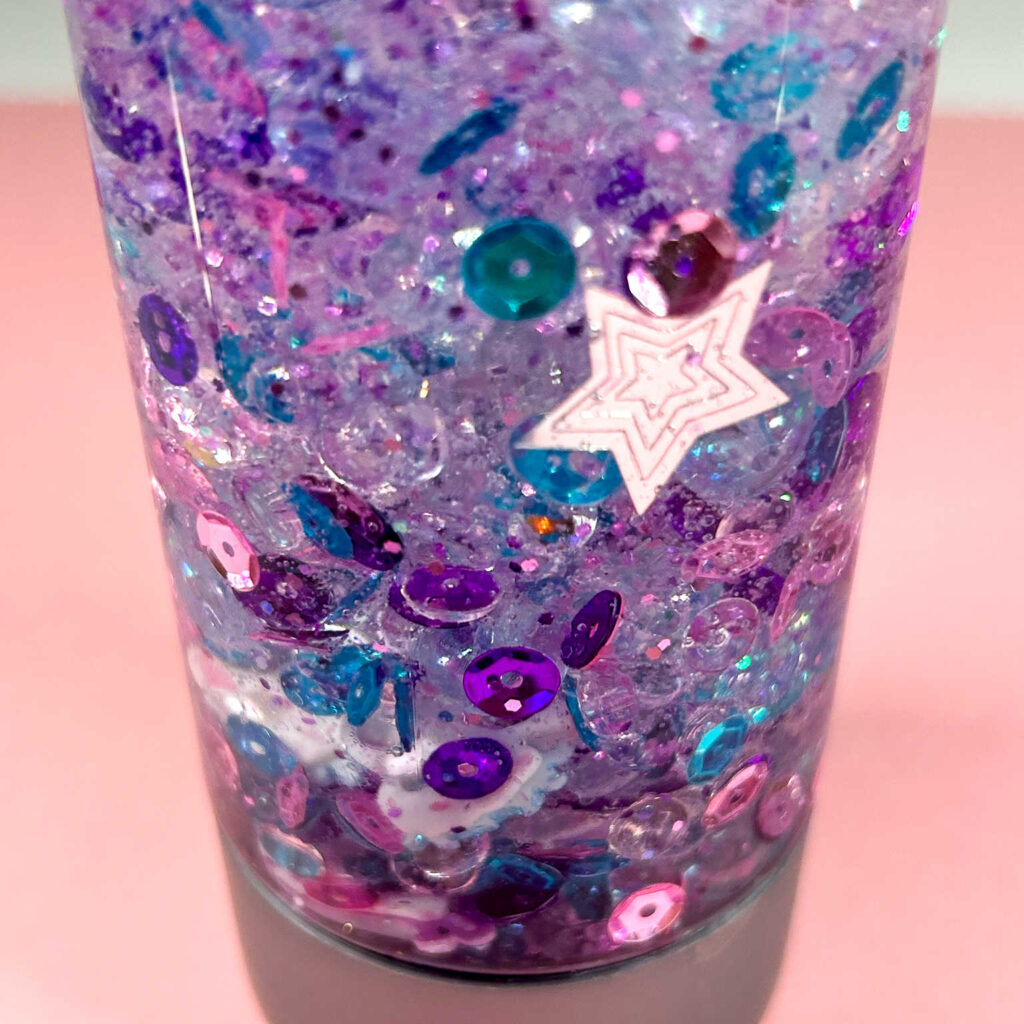 close up of pink purple blue glitter sensory bottle with stars