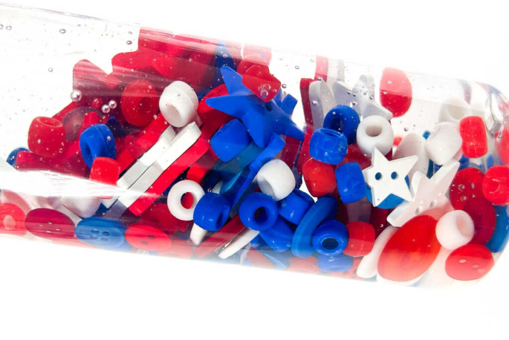 close up of sensory bottle with red white and blue buttons and beads