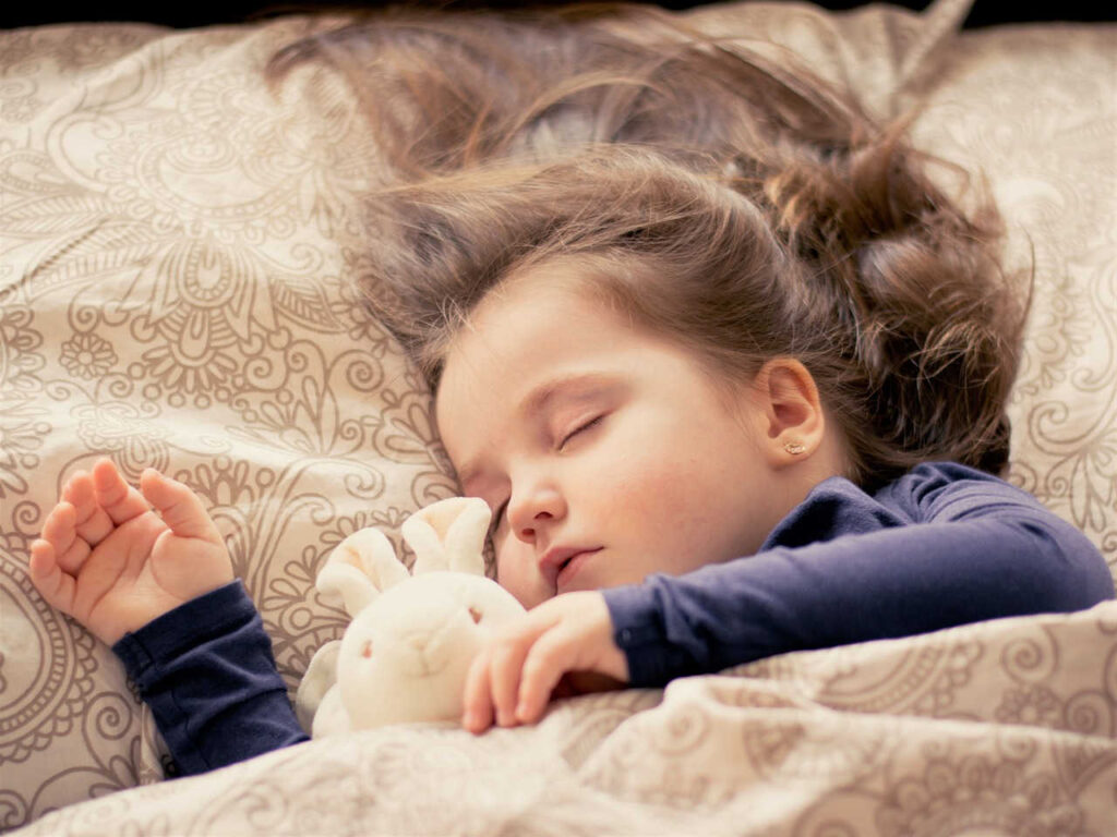 toddler girl sleeping with her stuffed rabbit