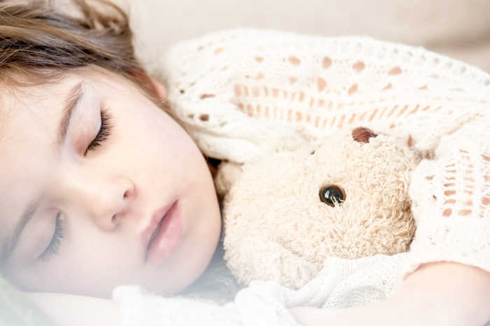 child snuggling with teddy bear sleeping