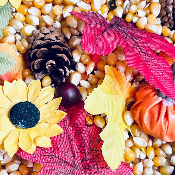 close up of all fall winter play basket, fall leaves, sunflowers, pinecones, red berries, popcorn kernels, gold sequins