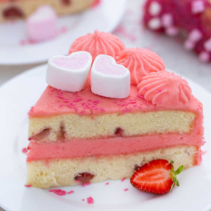 slice of pink barbie cake with strawberry and heart marshmallows