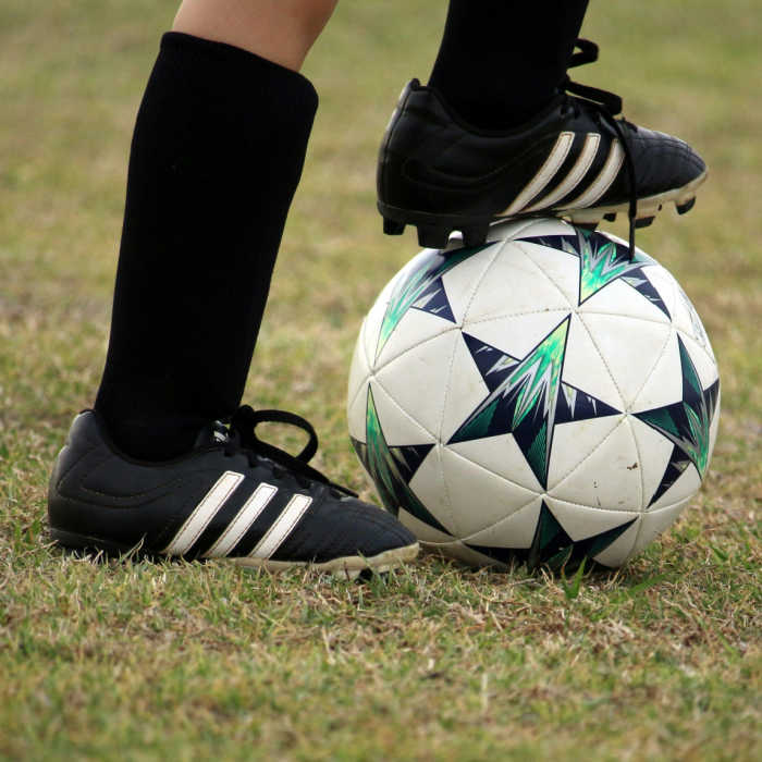 child wearing soccer shoes with foot on top of soccer ball