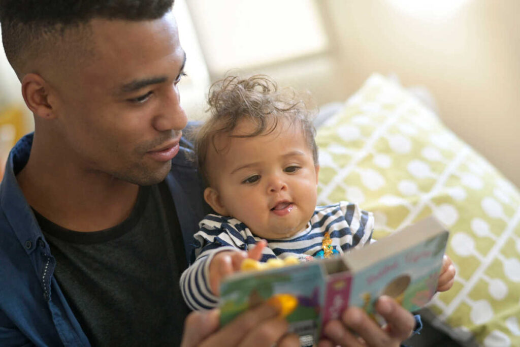 father reading to baby infant board book