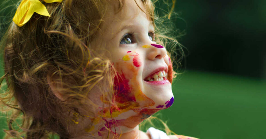 child smiling covered in paint