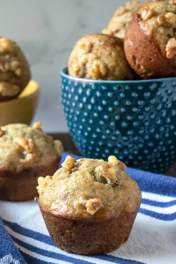Banana Nut Muffins combine mashed bananas, melted butter and chopped walnuts into a simple batter that bakes up soft with lightly golden tops.