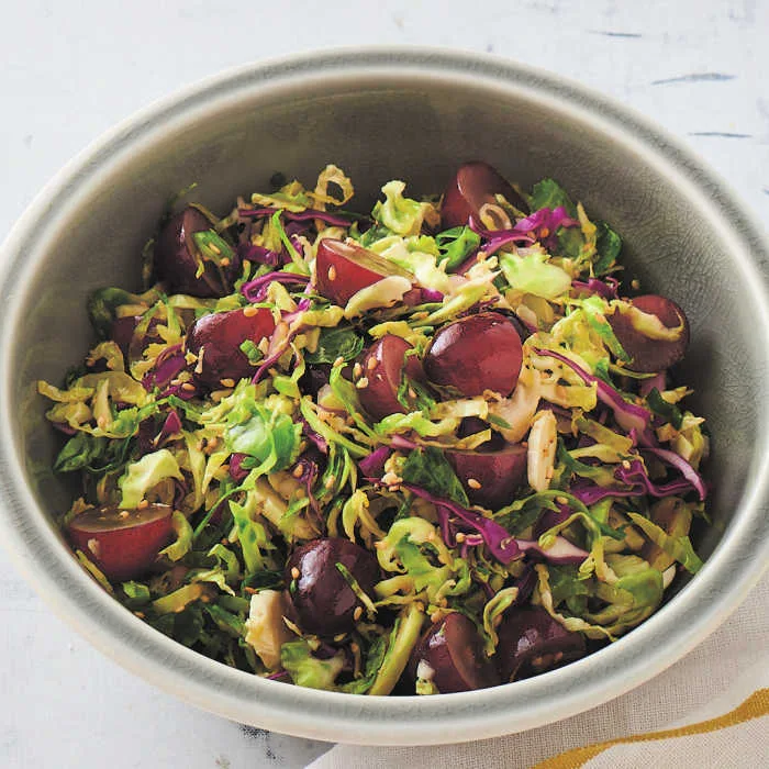 Brussels Sprout Slaw is a crisp, colorful salad with a balance of sweet grapes, tangy vinaigrette and nutty sesame flavors, perfect for a fresh, make-ahead side.
